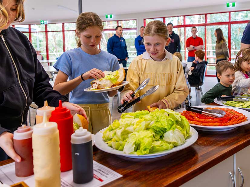 Two girls serving themselves lunch in the canteen
