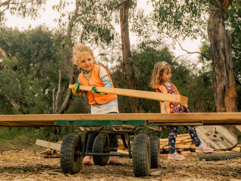 Two children building with wooden planks at a Mini Forest Skills program