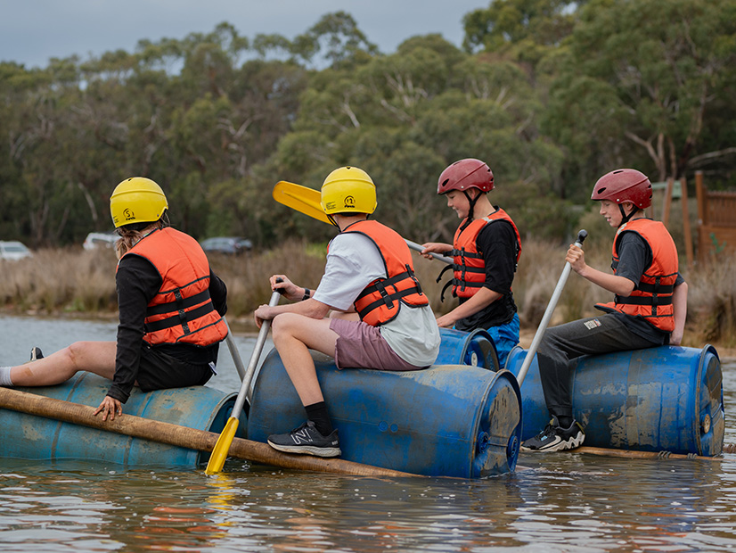 Group of young people rowing a raft they've built