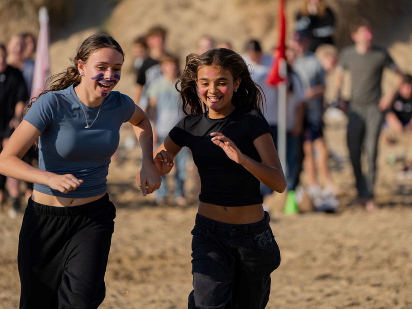 Two school group students running during a beach activity