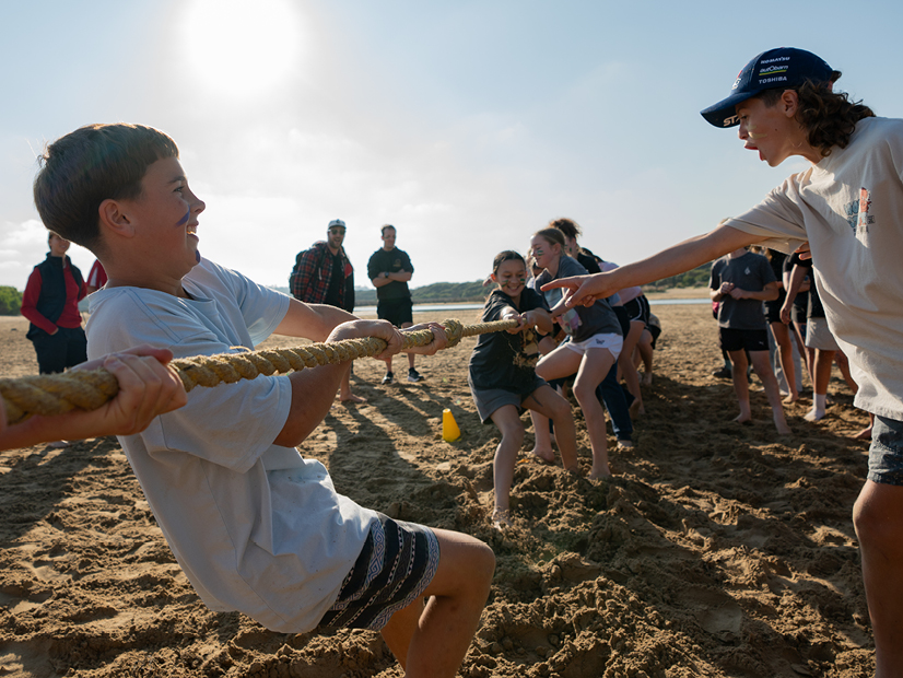 Young people playing tug a war on the beach