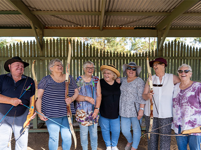 Group of active adults holding bows and posing for camera at Lady Northcote