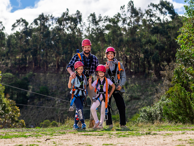 Parents and their two daughters wearing helmets and harnesses for a camp activity