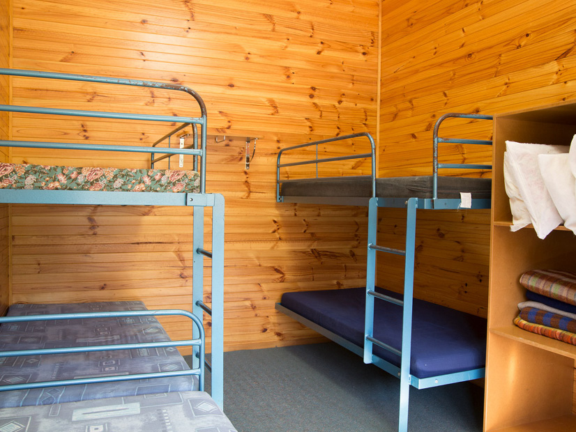 A bunk room at Howmans Gap Alpine Centre with five beds.
