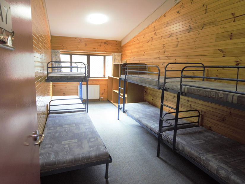 A bunk room at Howmans Gap Alpine Centre with seven beds.