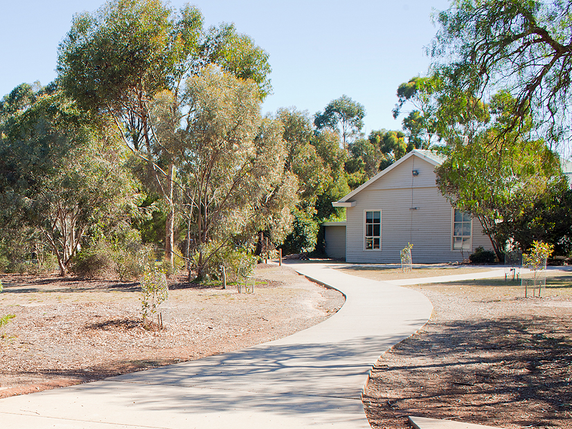 Exterior image of a white wooden building surrounded by trees.