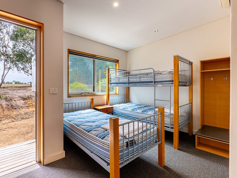 Bedroom with a bunk bed, single bed, wardrobe and scenic view at Lake Dewar Discovery Camp