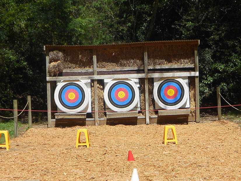 An archery range with three targets is surrounded by trees.